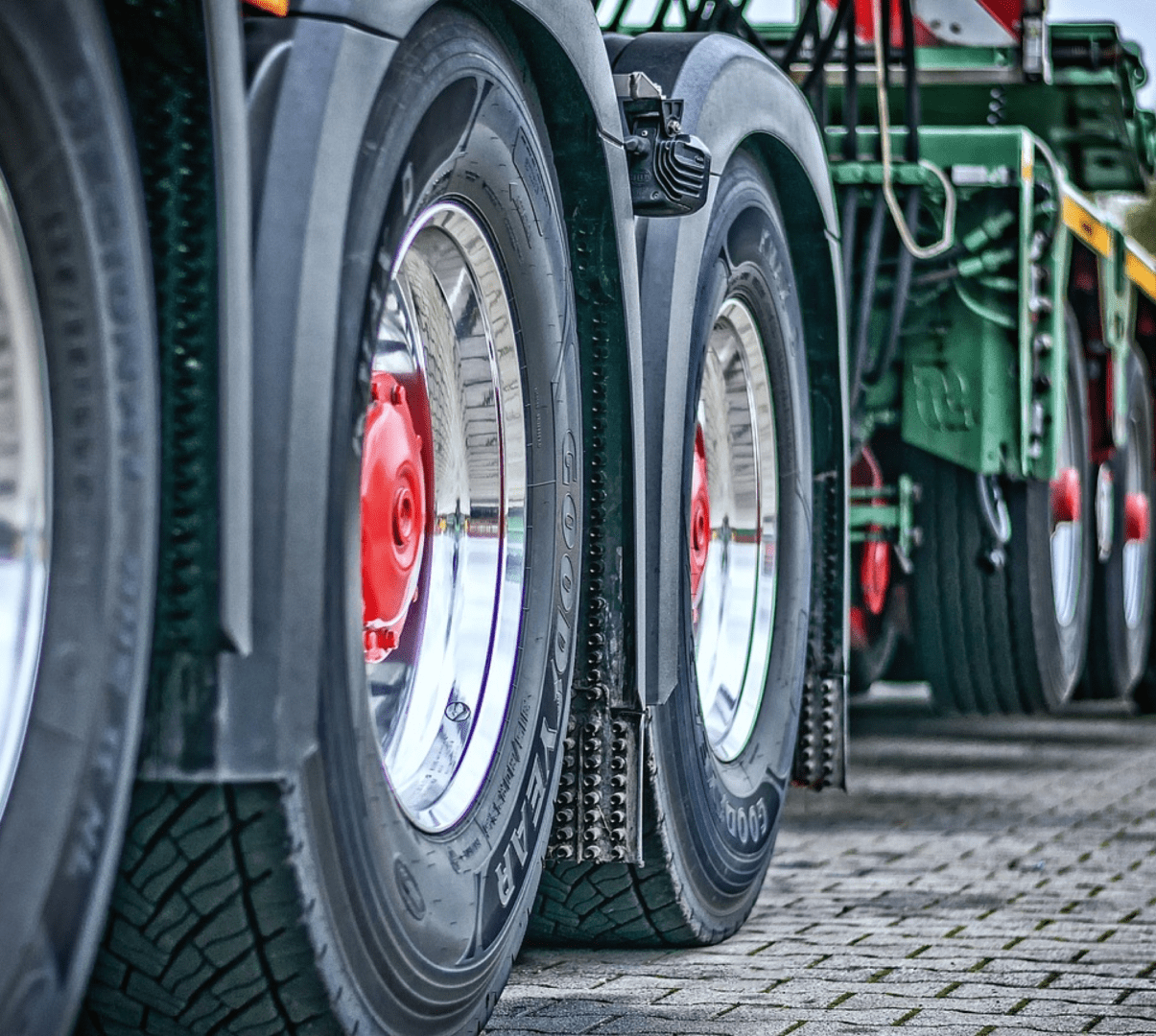 Close-up of the wheels and tires of a large vehicle, showing multiple axles parked on a paved surface.